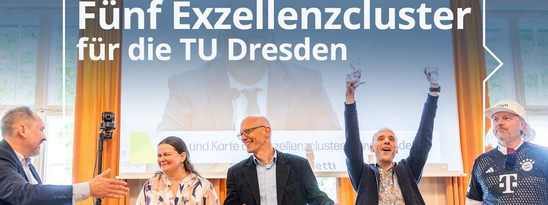 © TUD Bild von 5 jubelnden Personen vor einem an die Wand projezierten Video einer Pressekonferenz